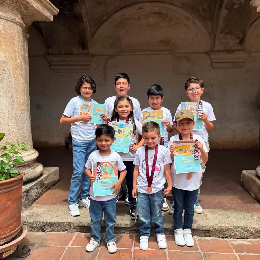 Grupo de Kiddies con medallas y diplomas de un concurso de arte, frente a unas columnas coloniales
