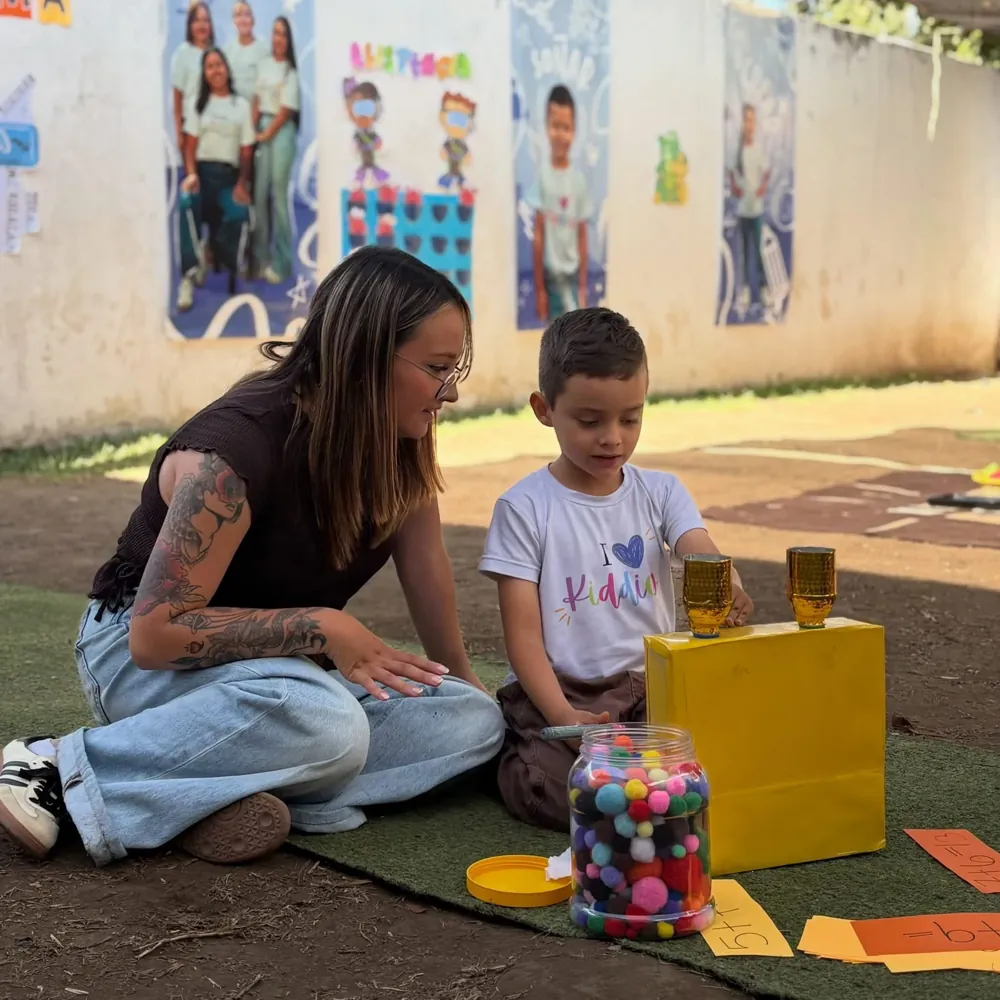 Mamá sentada junto a su hijo mientras resuelve sumas con pompones de colores en las Aulas abiertas