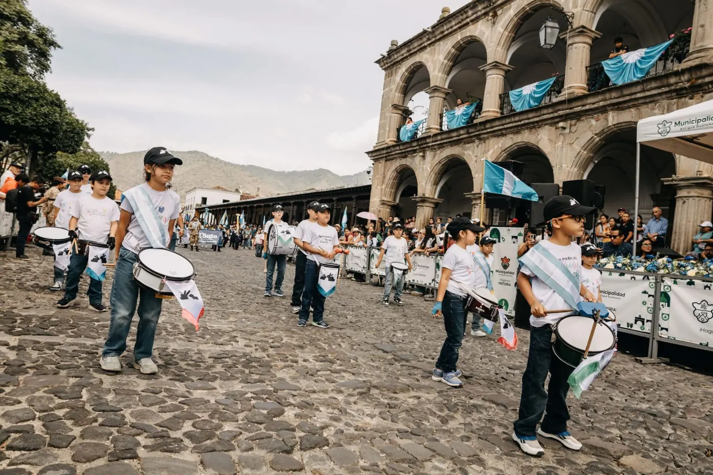 Banda de Kiddies Club tocando tambores en el desfile frente al Palacio del Ayuntamiento de La Antigua Guatemala