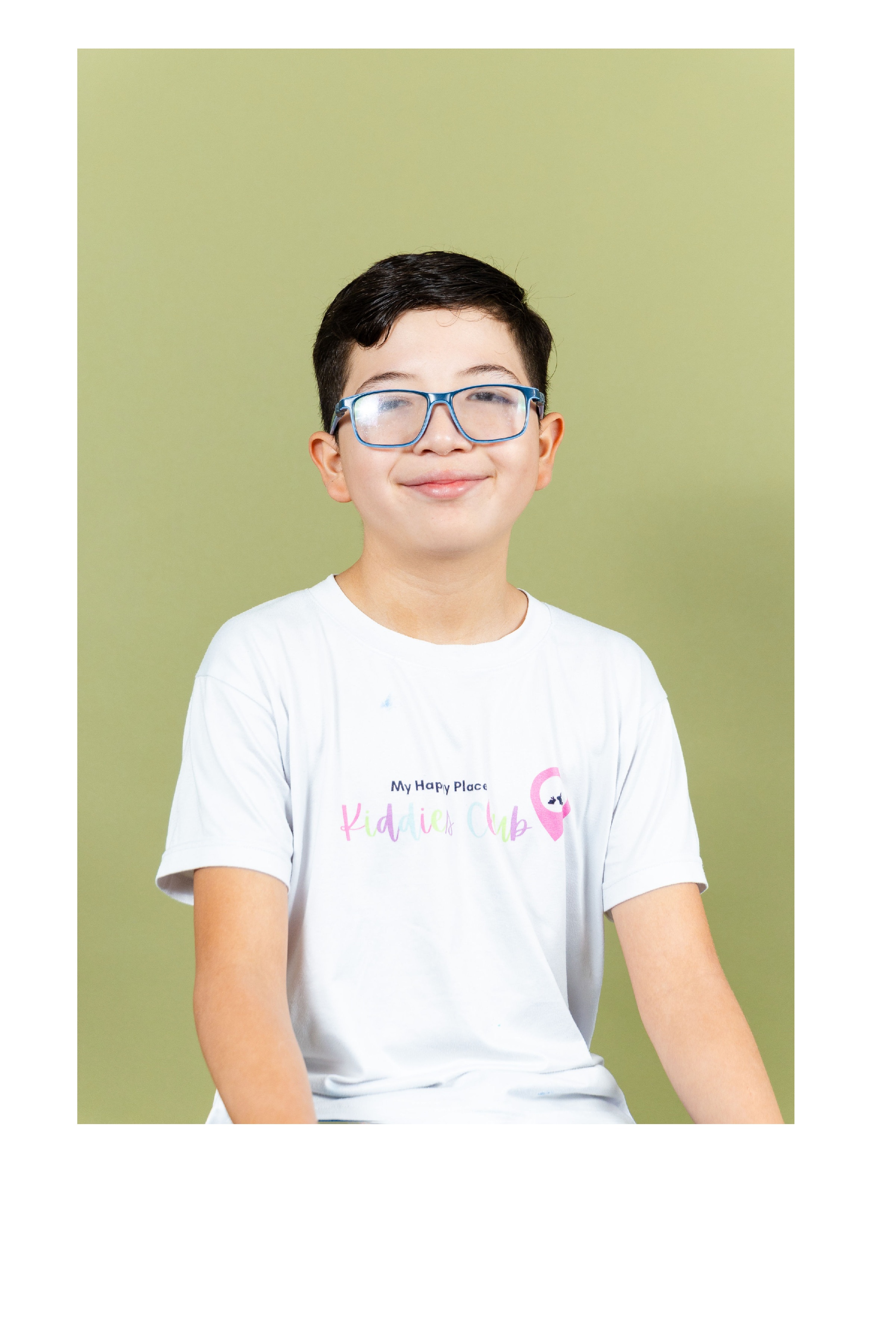Alumno de Primaria con lentes sonriendo con su camiseta de Kiddies Club
